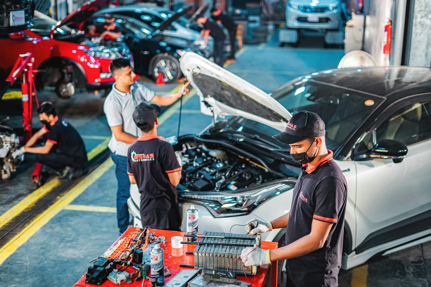 Mechaniker reparieren Fahrzeuge in einer belebten Autowerkstatt.