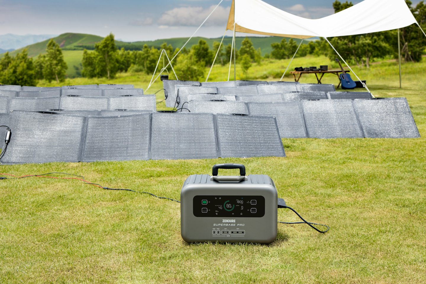 Tragbare Powerstation, die auf einem grasbewachsenen Feld an Solarmodule angeschlossen ist.