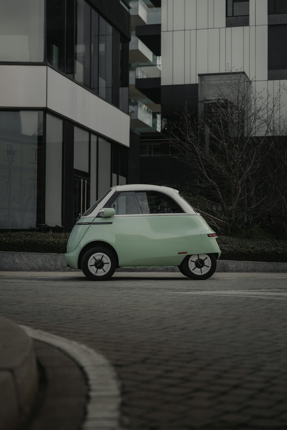 Ein mintgrüner und weißer Elektroauto, das auf der Straße geparkt ist.